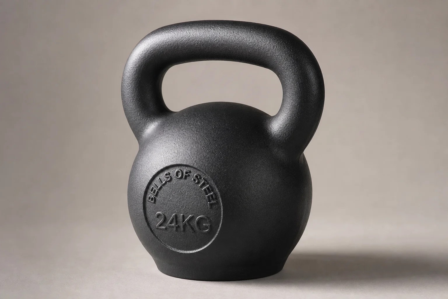 Five kettlebells of varying weights and finishes arranged on concrete surface