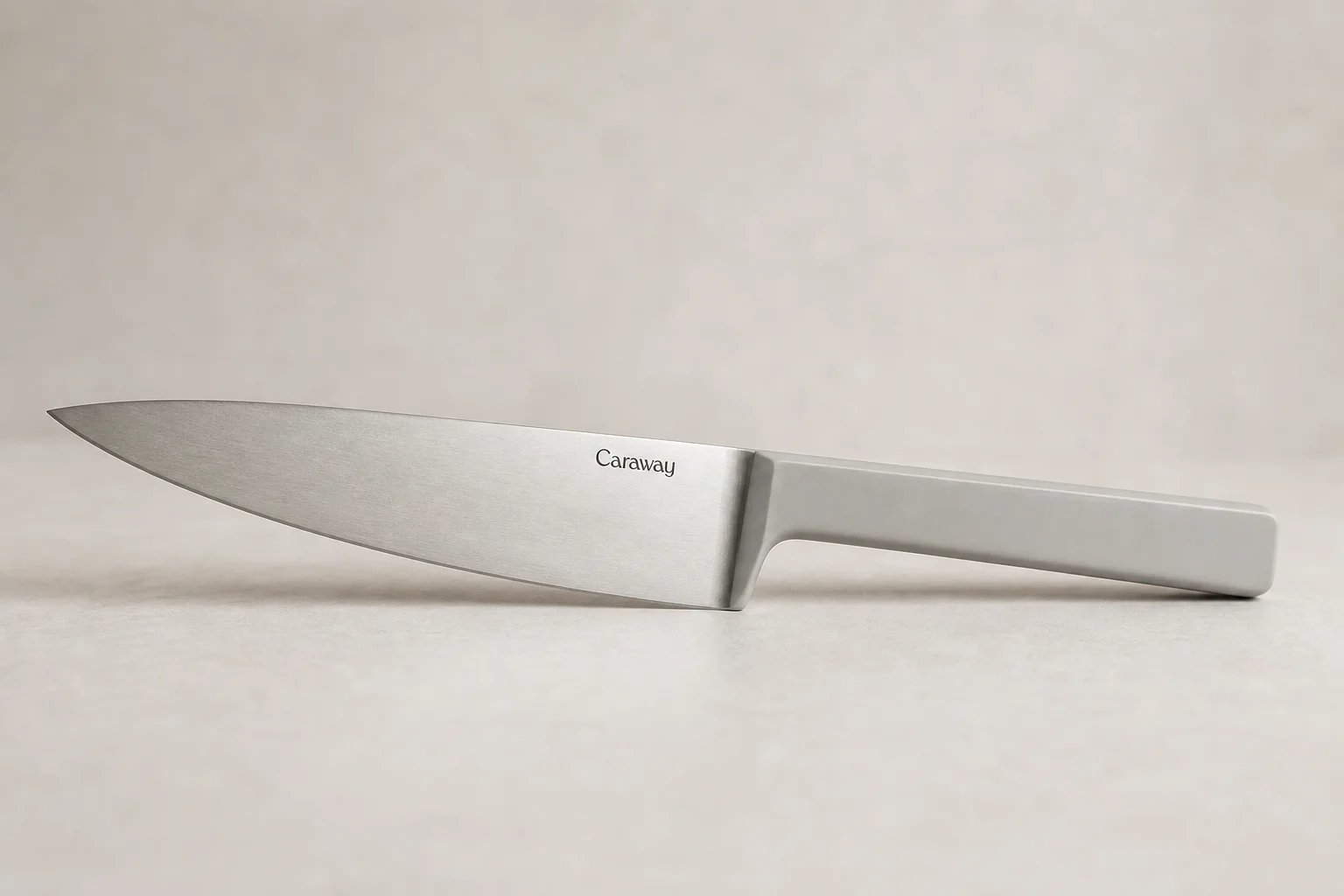 Collection of eight chef's knives arranged diagonally on concrete surface showing various styles and price points