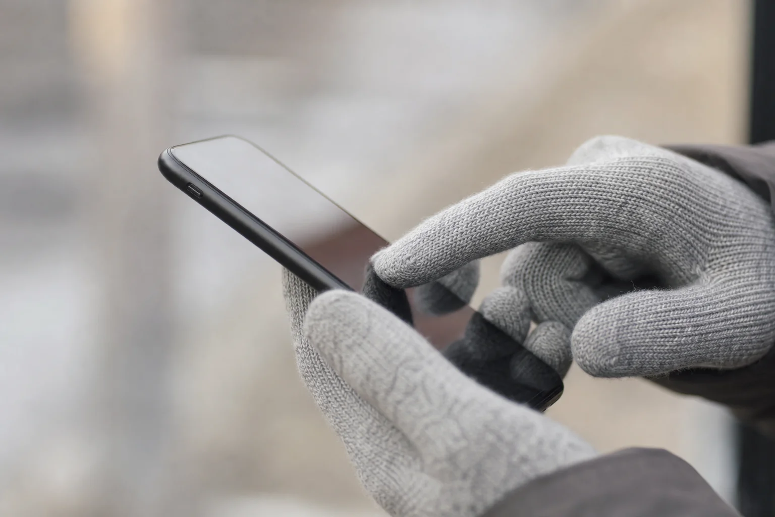 Gloved hand using smartphone touch screen with index and thumb