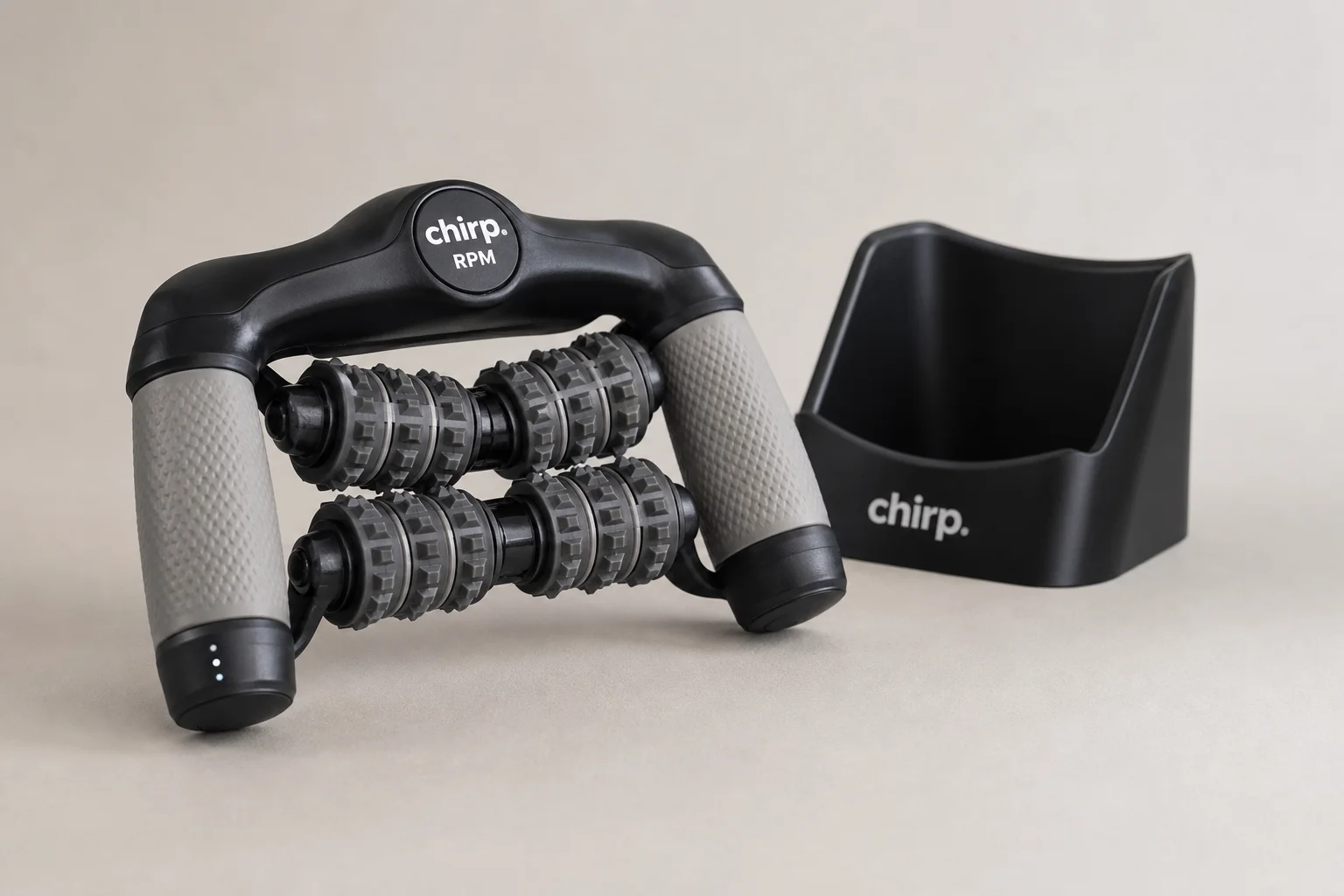 Chirp RPM rolling percussive massager with handles and hands-free cradle base on neutral backdrop