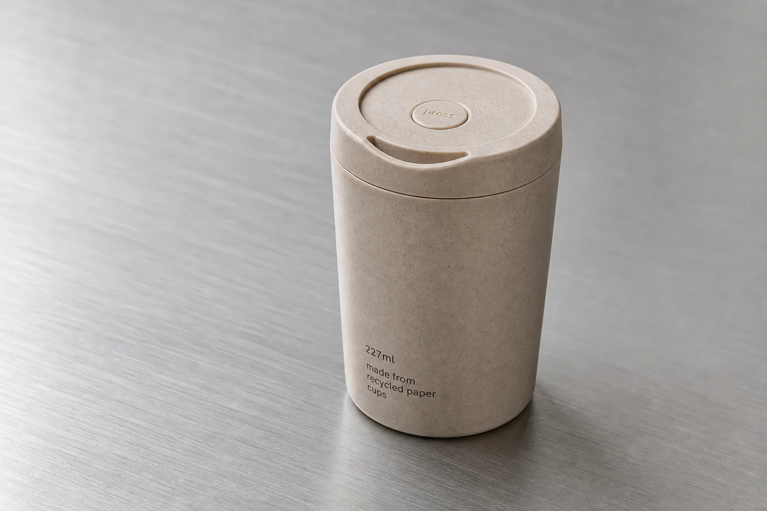Eight reusable coffee cups arranged on concrete surface showing variety of materials and designs