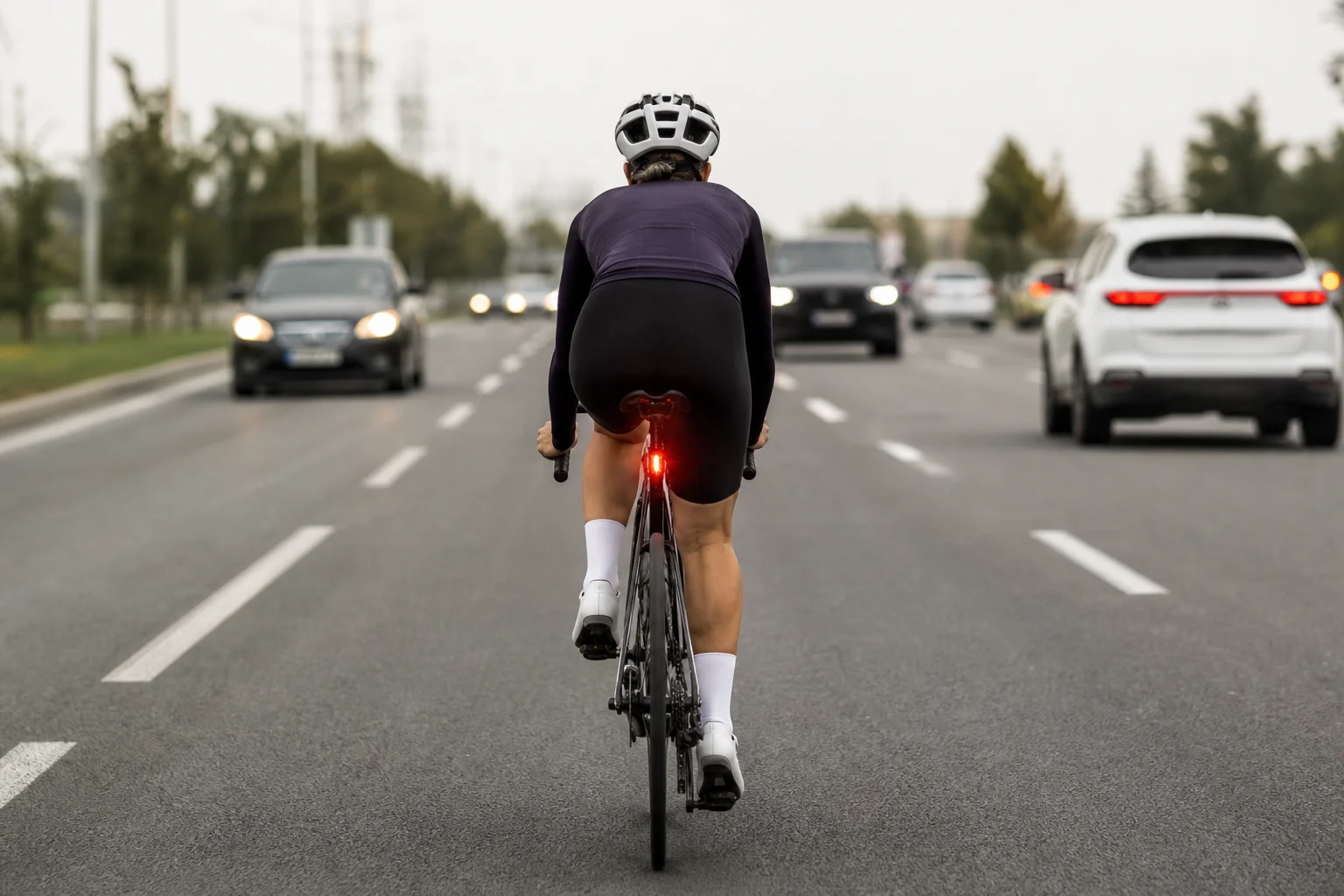 Cyclist on multi-lane road with multiple vehicles visible behind