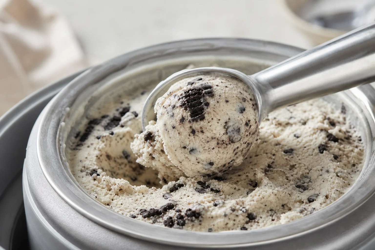 冰淇淋勺從攪拌桶中挖取含有 Oreo 碎片的香草冰淇淋