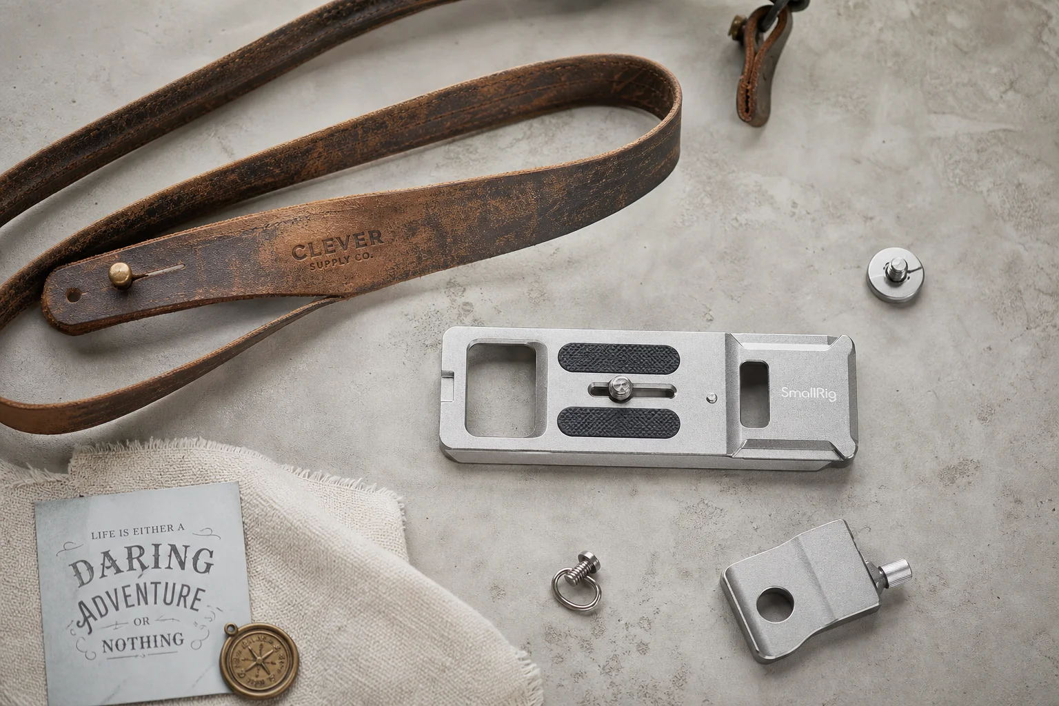 Overhead flat-lay of vintage leather camera strap and metal accessories on concrete