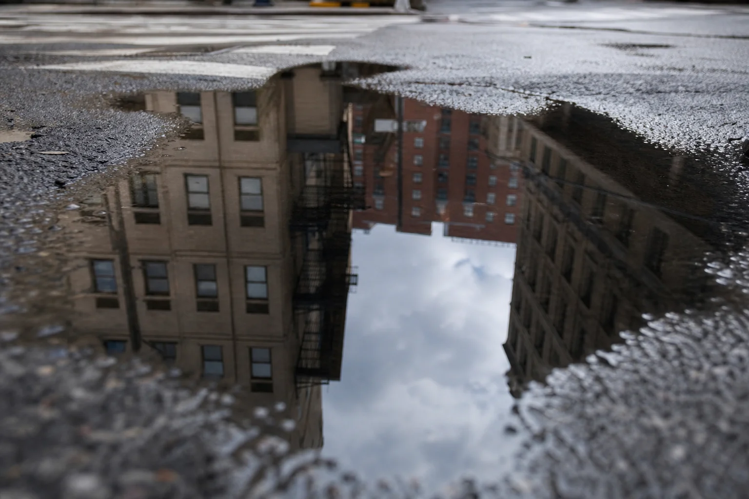 Street scene with reflective puddle showing camera lens sharpness and polarizing filter effect