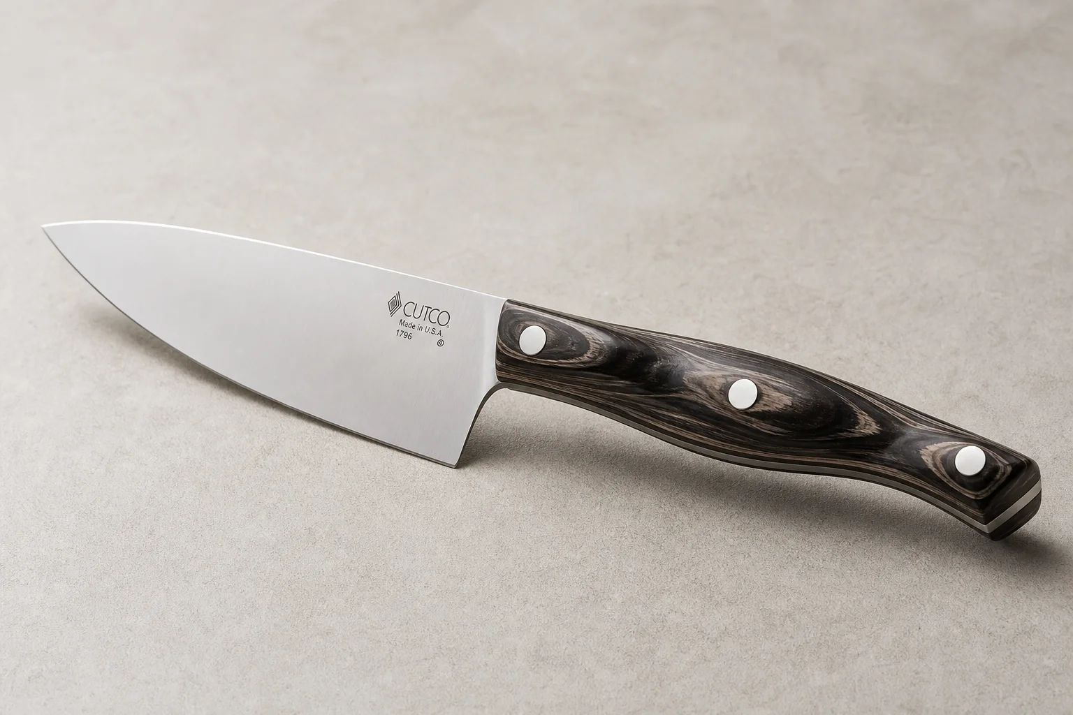 Collection of eight chef's knives arranged diagonally on concrete surface showing various styles and price points