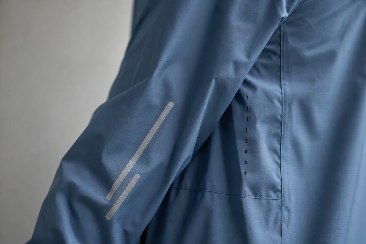 Close-up of reflective strips and ventilation cuts on a blue rain jacket