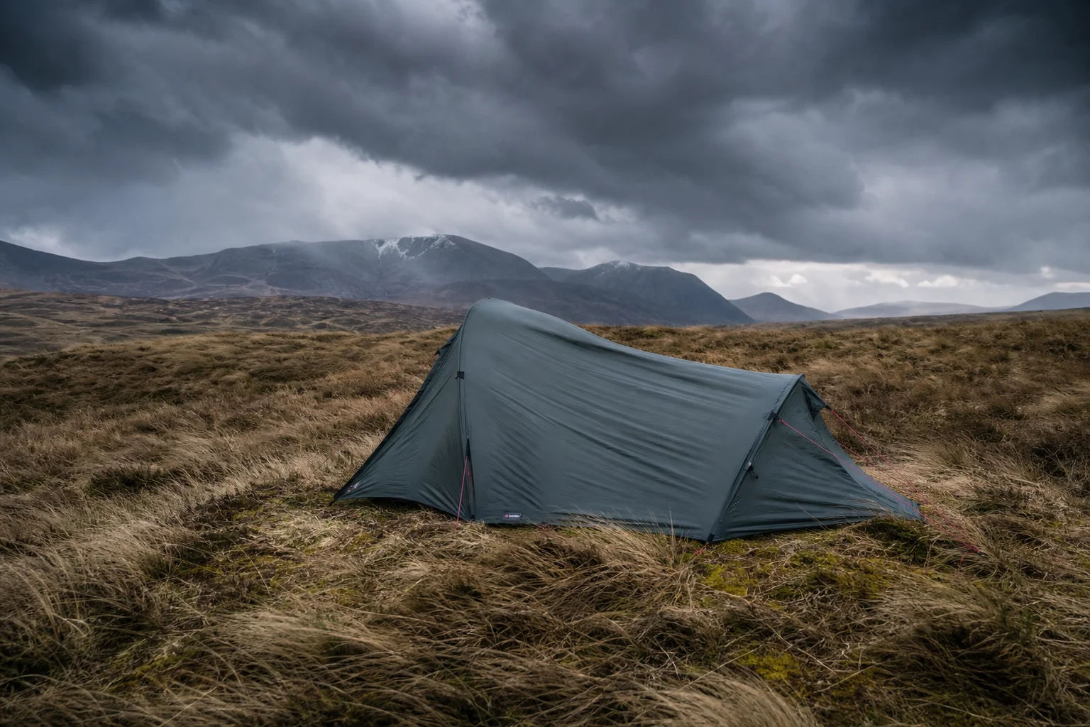 Ultralight tent pitched on moorland during gale-force wind conditions with storm clouds