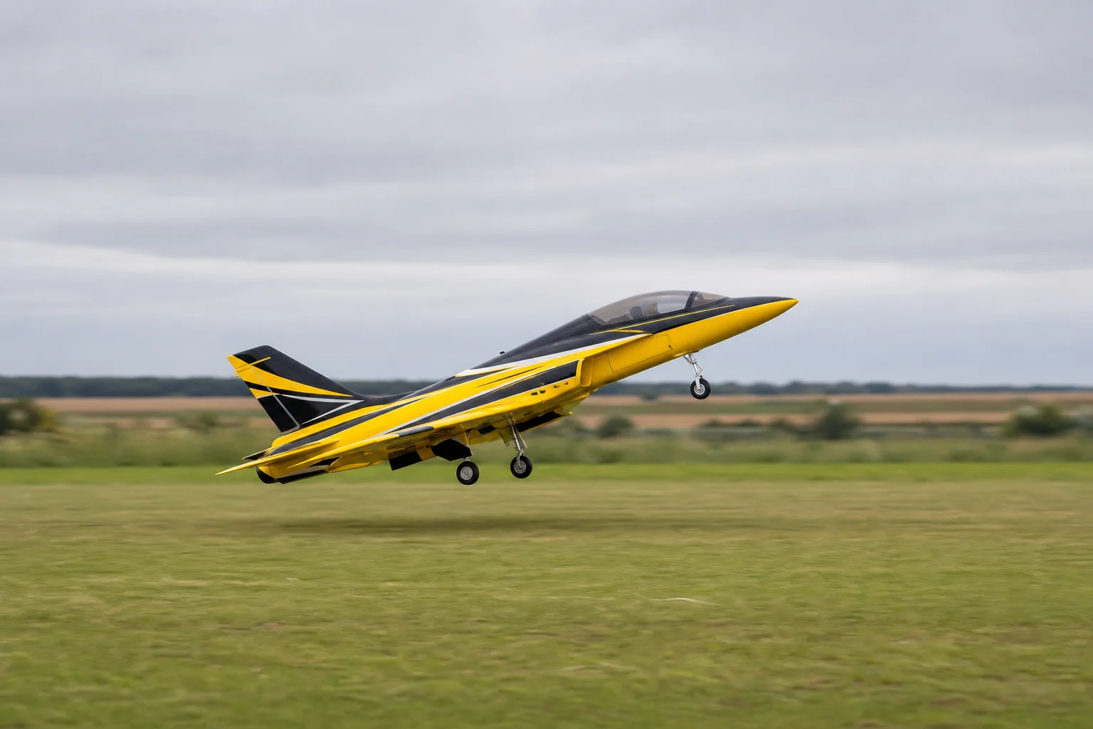 RC jet taking off from grass field with nose lifting