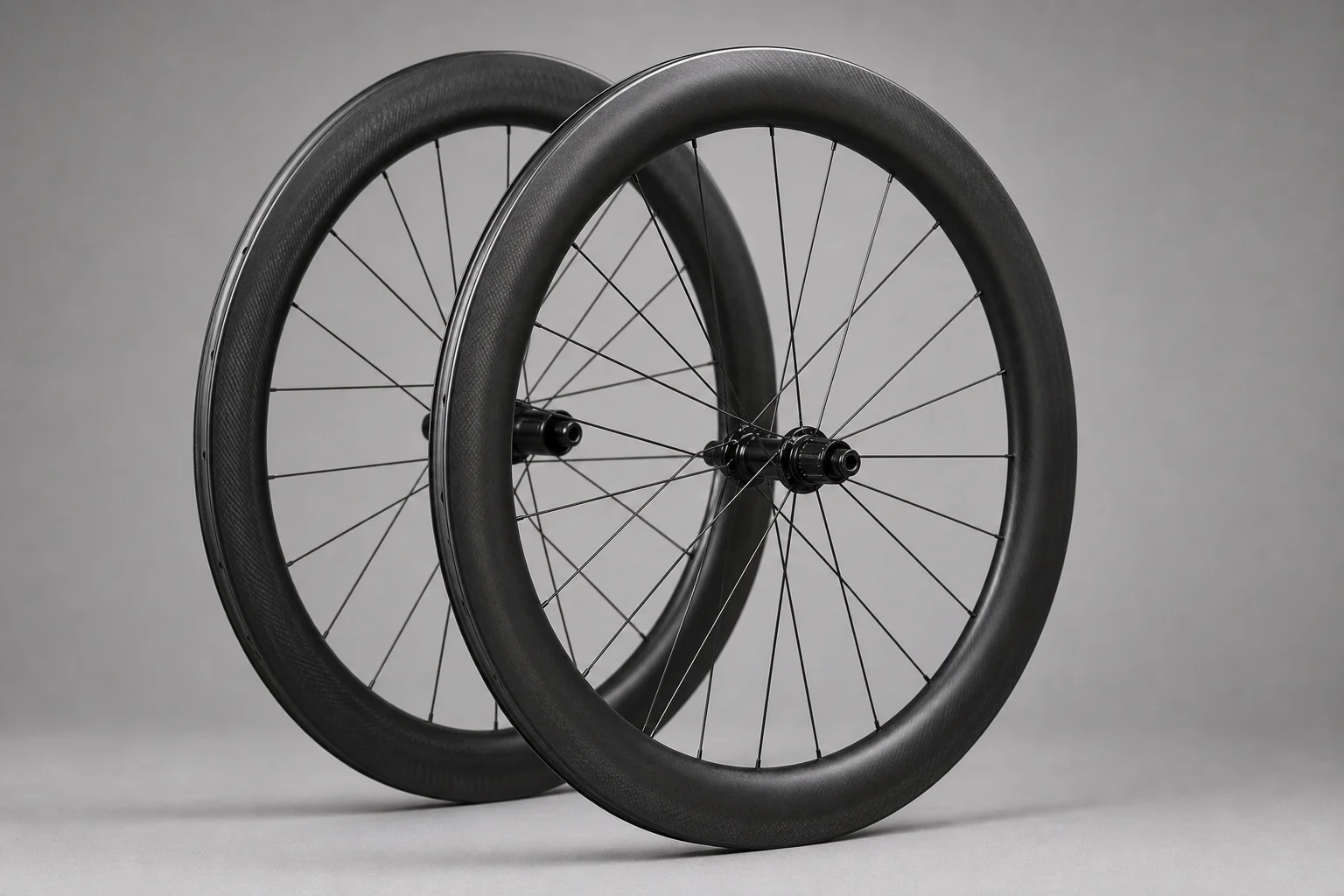Cycling accessories flat-lay including carbon wheels, handlebar light, and bib shorts on concrete