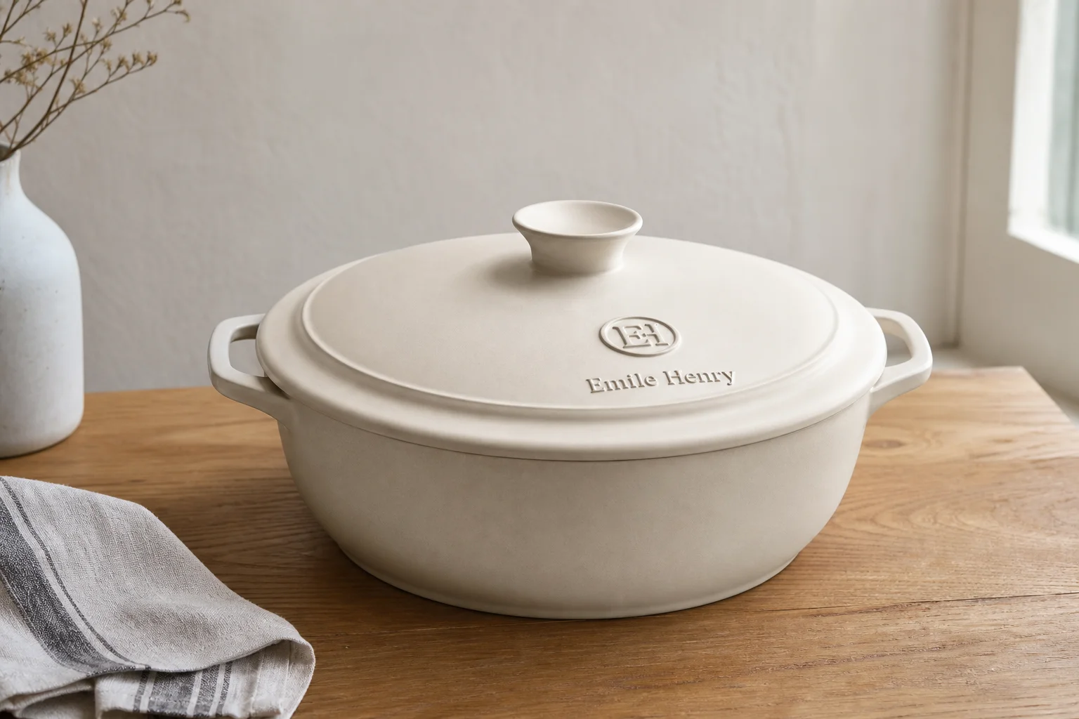 Three Dutch ovens in burgundy, cream, and red arranged on concrete surface
