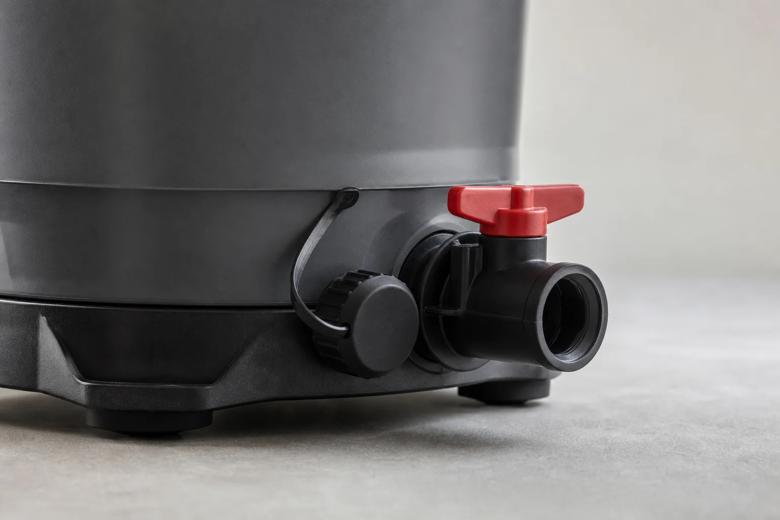 Canister filter drain plug and red valve handle at the base