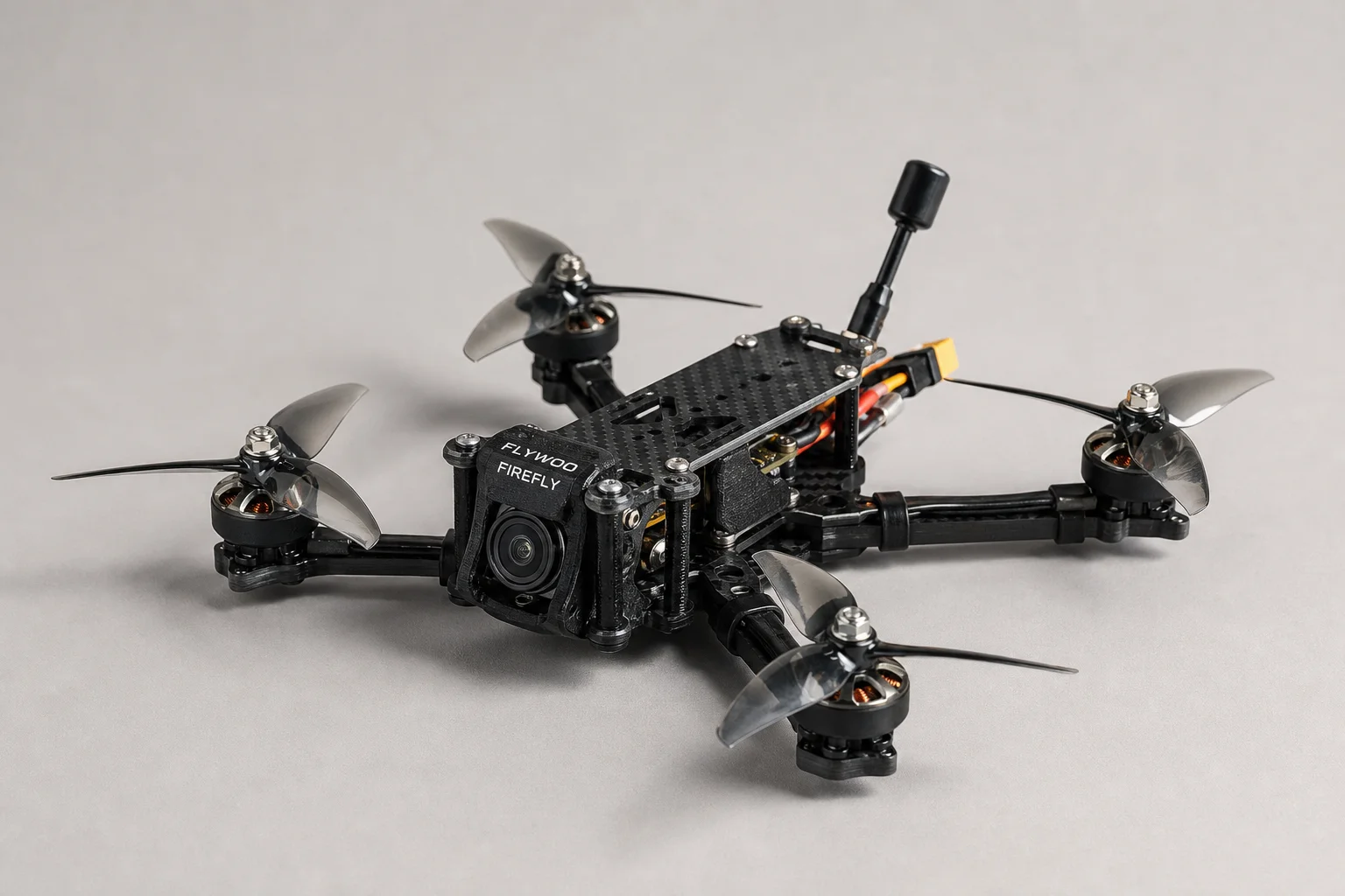 三台小型 FPV 無人機與運動相機放置在混凝土表面上