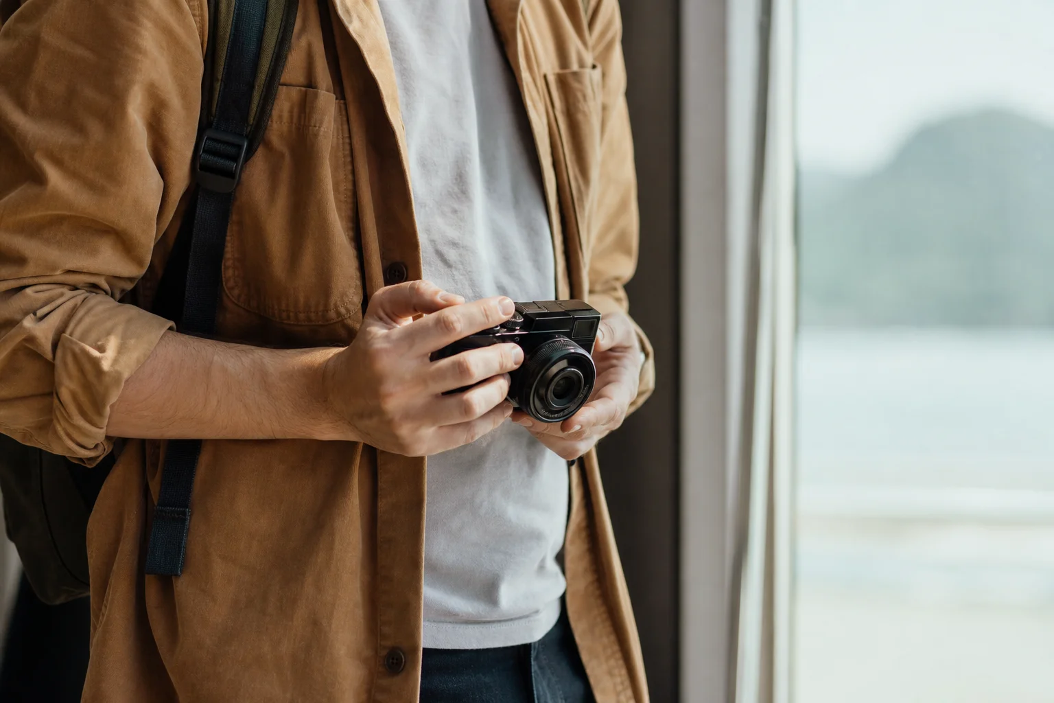 Photographe tenant un appareil photo hybride compact avec un objectif interchangeable en extérieur
