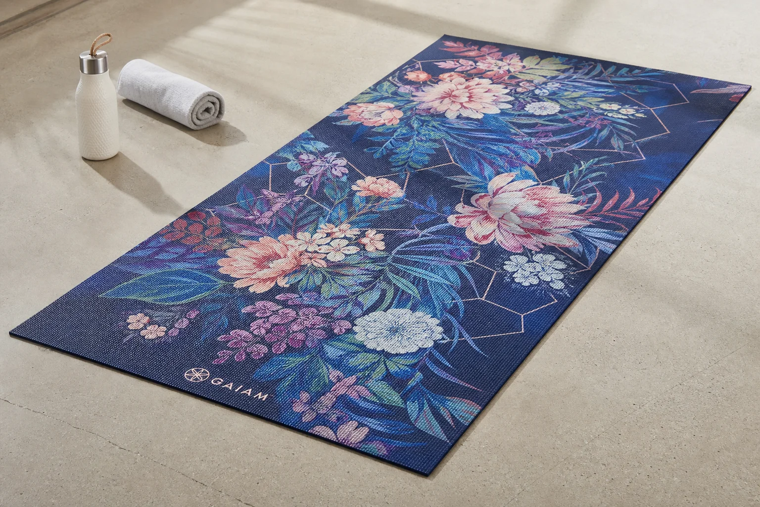 Seven different yoga mats arranged on a wooden floor showing variety of styles and colors