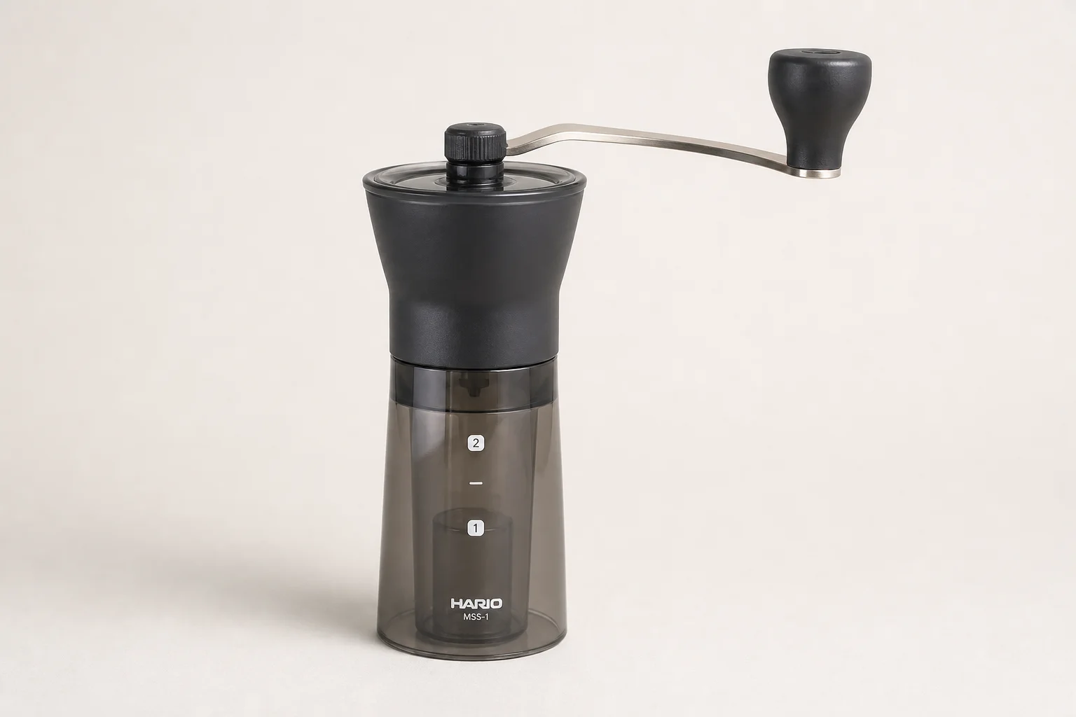 三款手搖磨豆機:Hario Slim、KINGrinder P1 與 Comandante 排列在水泥面上