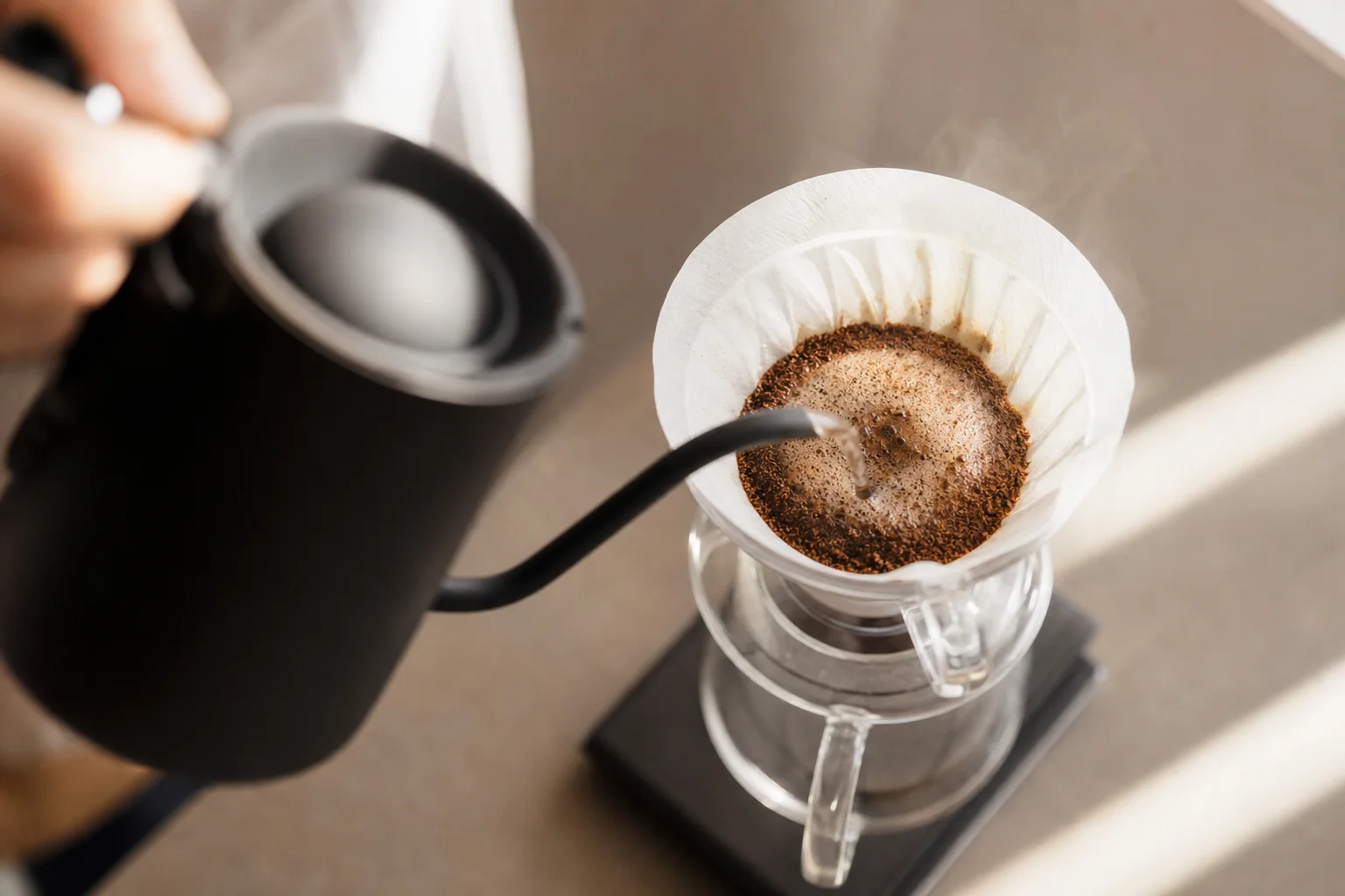 Hands pouring hot water in circular motion over coffee grounds in a V60 dripper