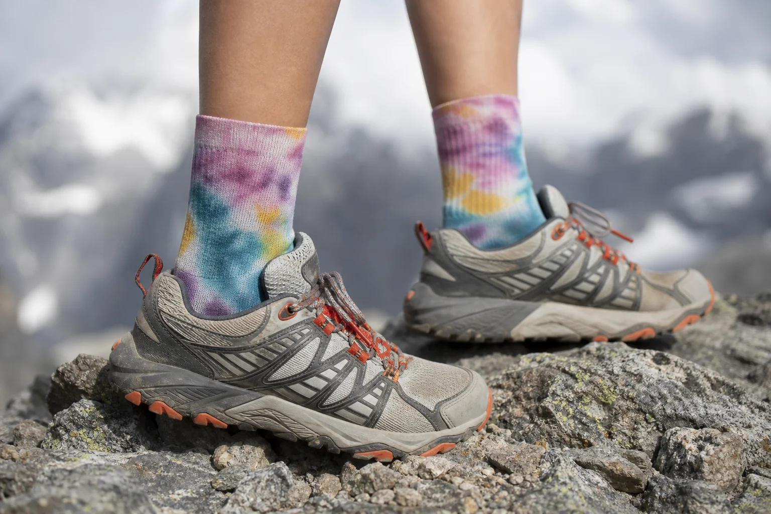 Runner's feet in tie-dye socks and trail shoes on rocky terrain