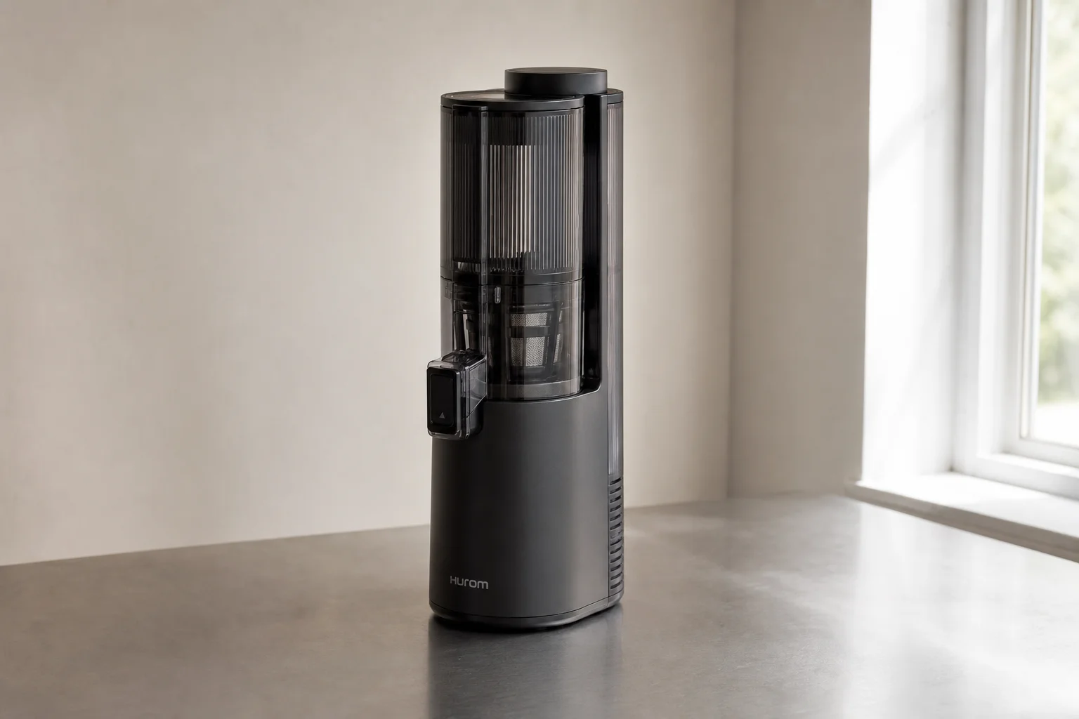Four cold-press juicers arranged on concrete surface showing different sizes and designs