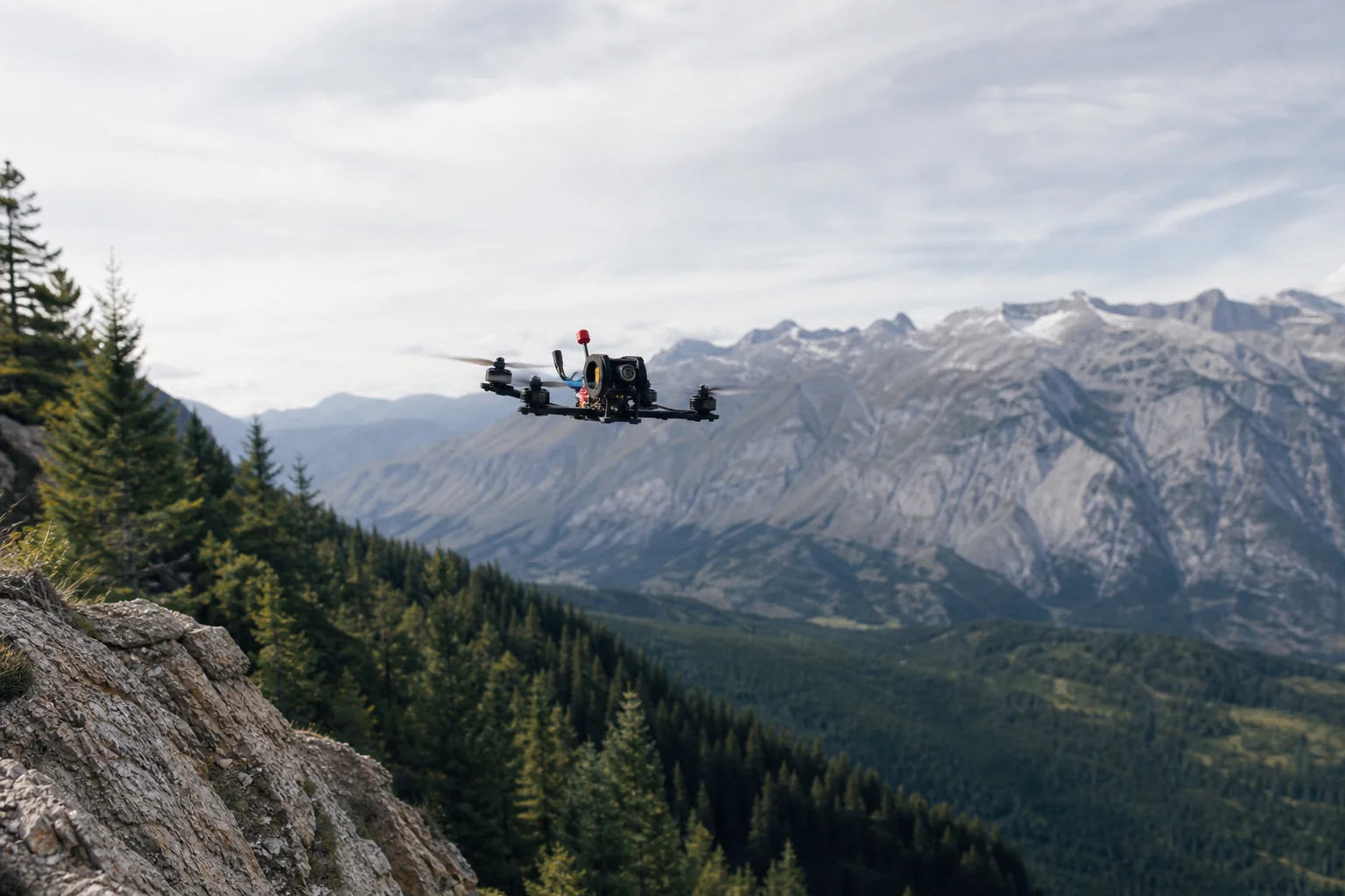 FPV 無人機飛越山區地形，下方為茂密森林