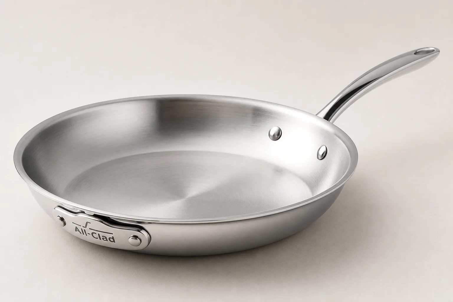 Premium All-Clad stainless steel fry pan with polished finish and soft reflections