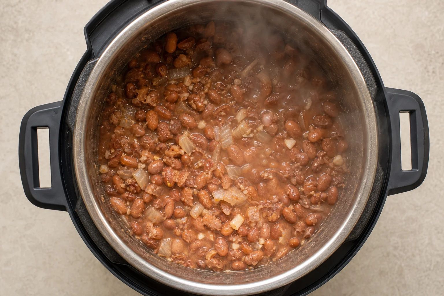 Cooked pinto beans in a multicooker pot with visible texture and aromatics
