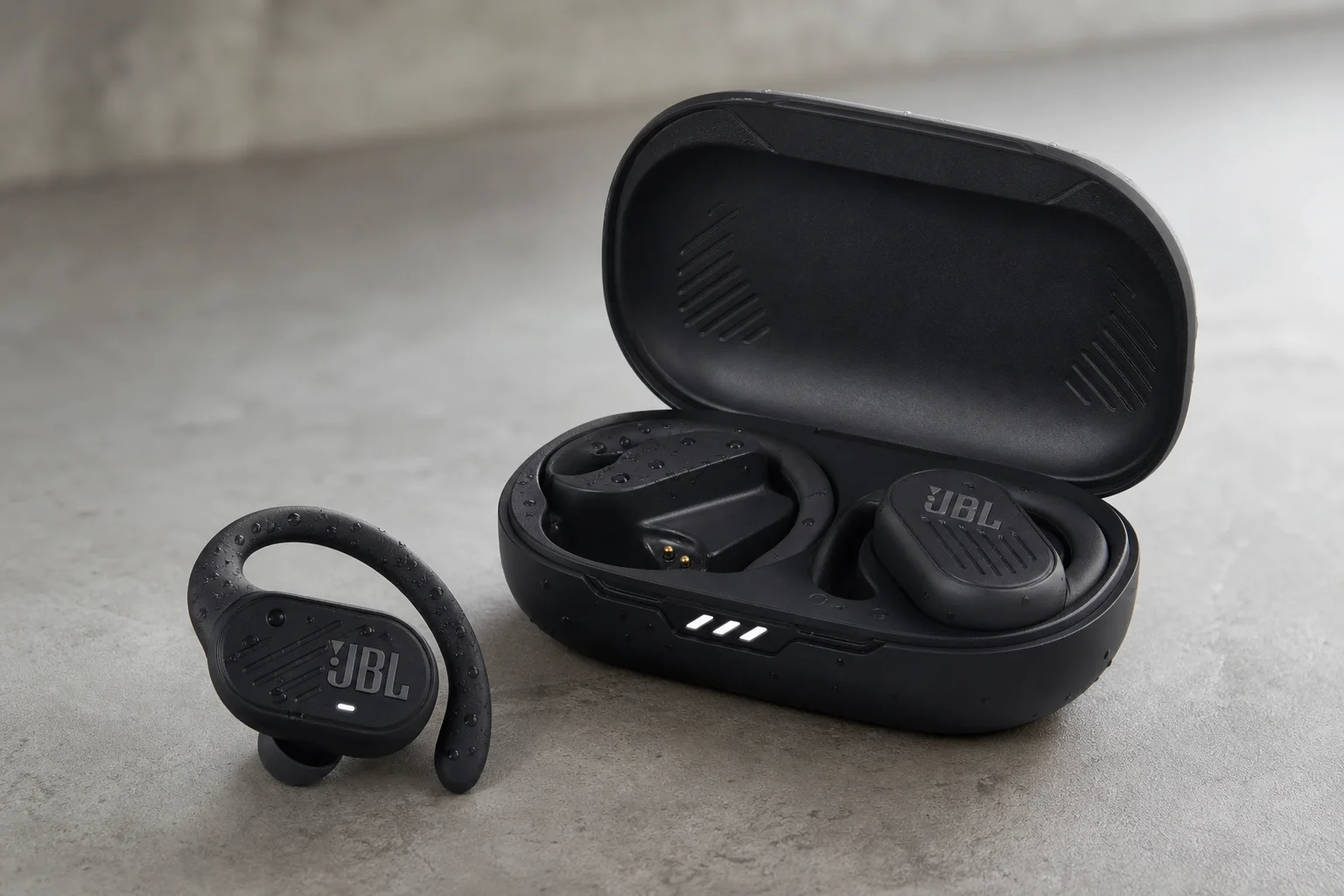Five JBL earbud models arranged on concrete surface