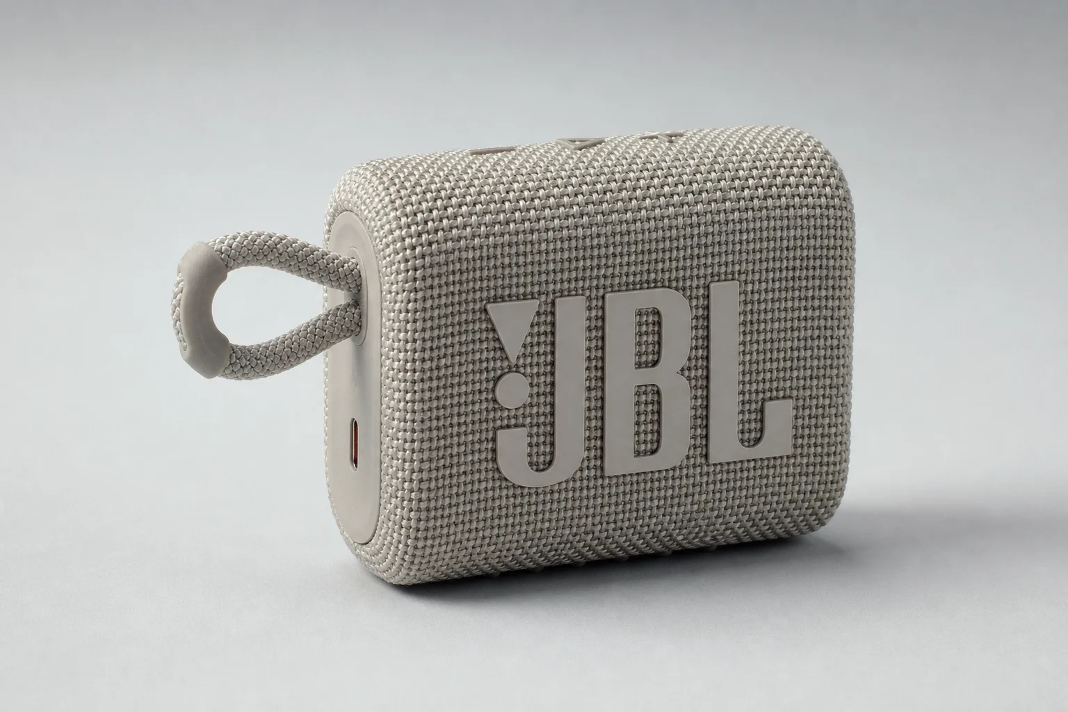 Five budget Bluetooth speakers arranged on concrete surface