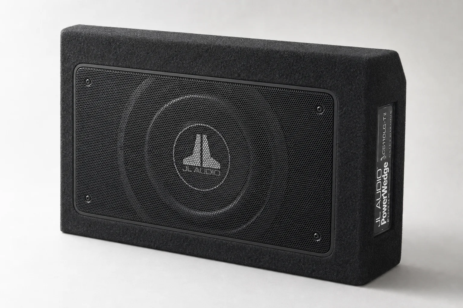 Seven car powered subwoofers of varying sizes arranged on grey surface