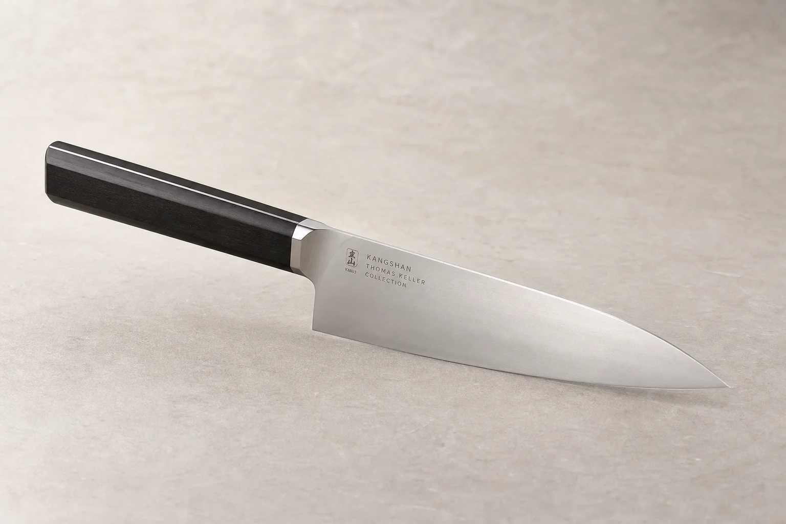 Collection of eight chef's knives arranged diagonally on concrete surface showing various styles and price points