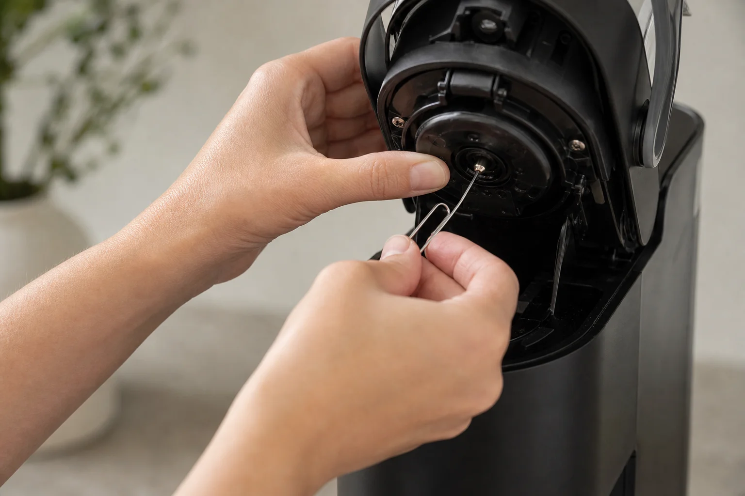 雙手使用迴紋針工具對 Keurig 針頭進行維護