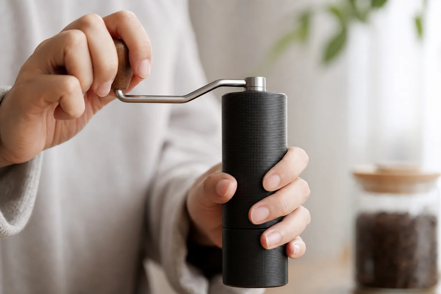 Hands grinding coffee beans with a hand grinder, showing ergonomic grip
