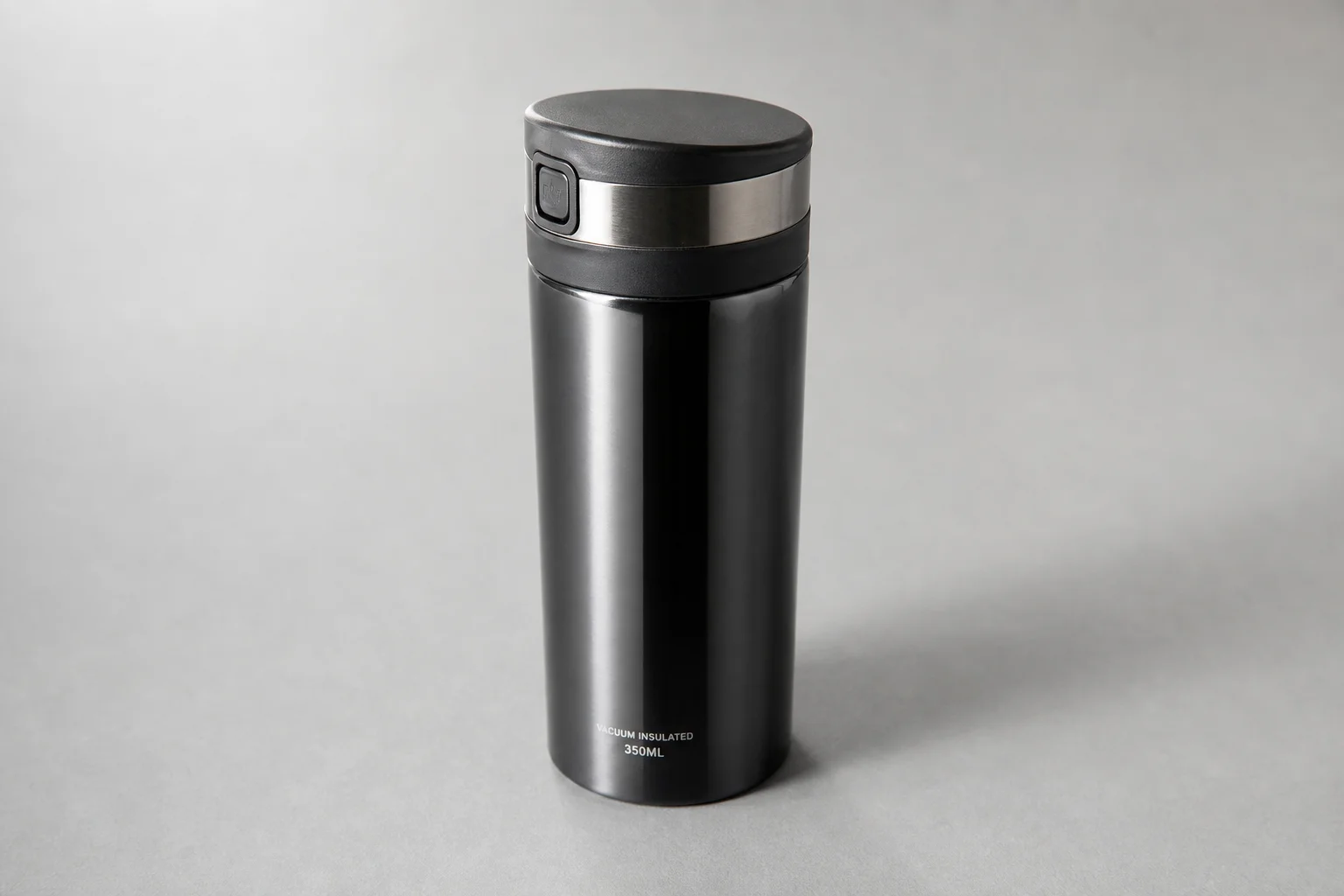 Eight reusable coffee cups arranged on concrete surface showing variety of materials and designs
