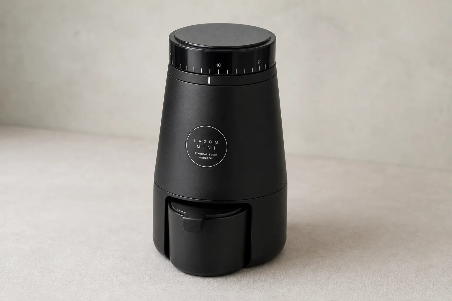 Seven espresso grinders of various sizes and styles arranged on concrete surface