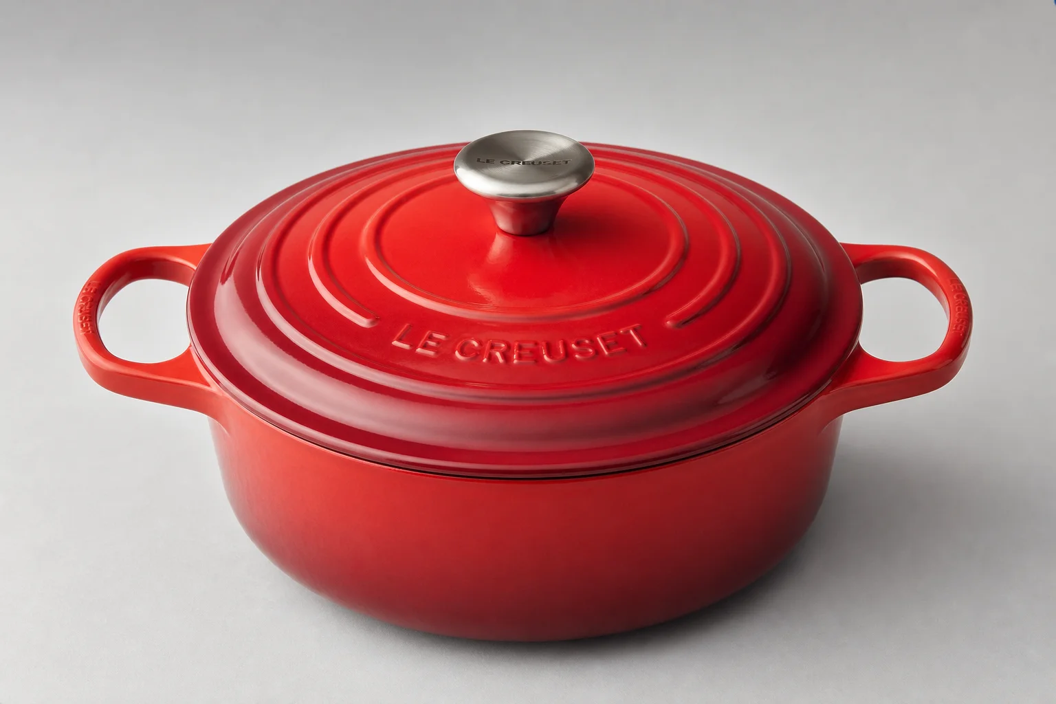 Three Dutch ovens in burgundy, cream, and red arranged on concrete surface