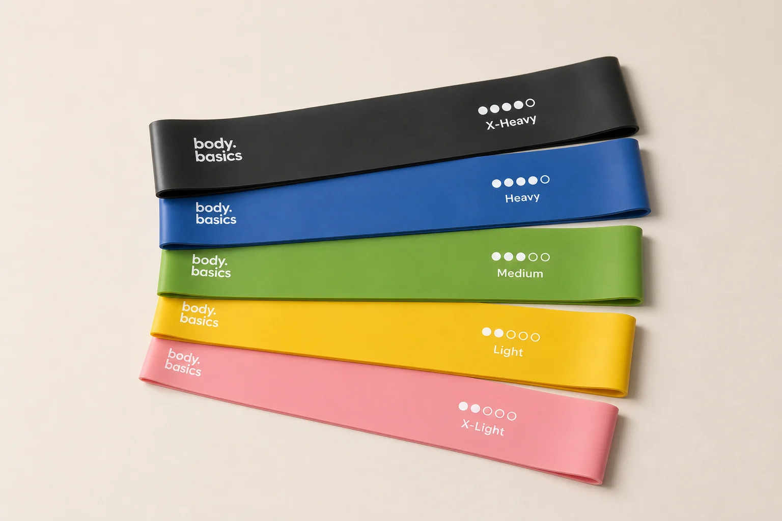 Five resistance band sets displayed on concrete surface showing different styles and colors