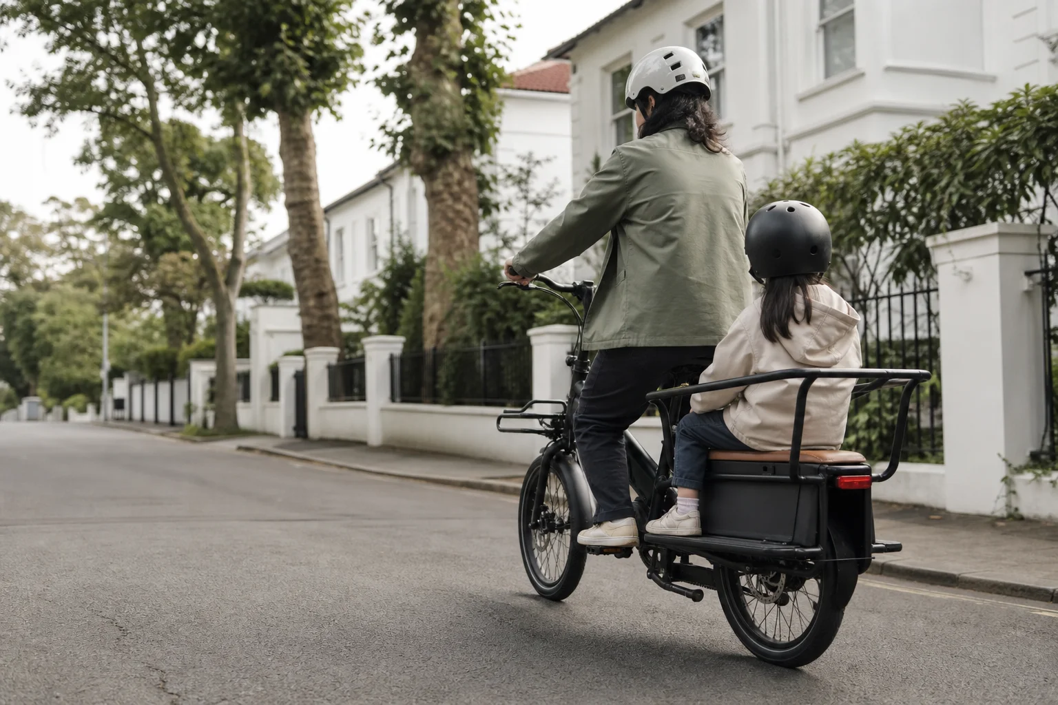 Parent and child on an e-cargo bike riding through a residential neighbourhood