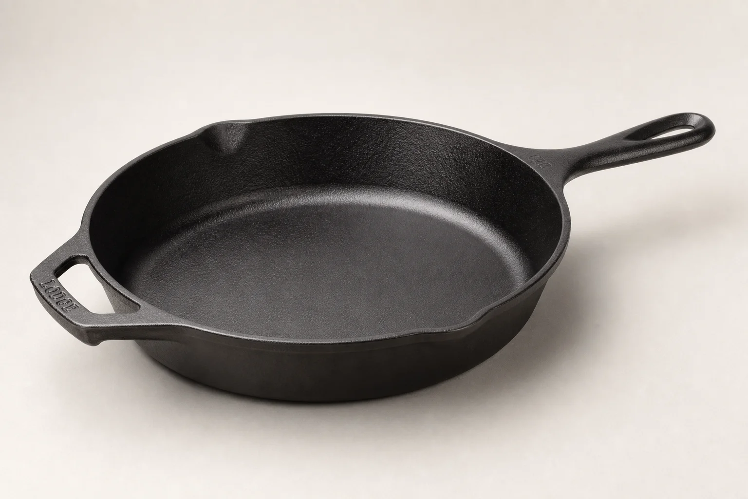 Two 12-inch cast iron skillets on concrete surface showing different finishes