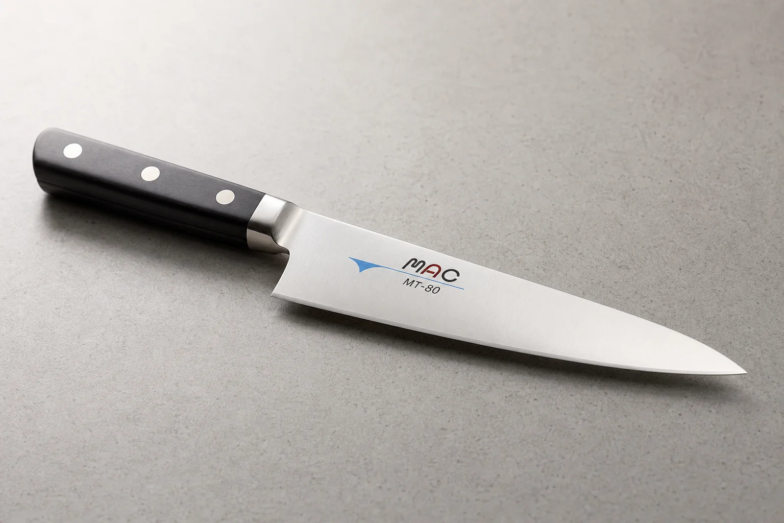 Collection of eight chef's knives arranged diagonally on concrete surface showing various styles and price points