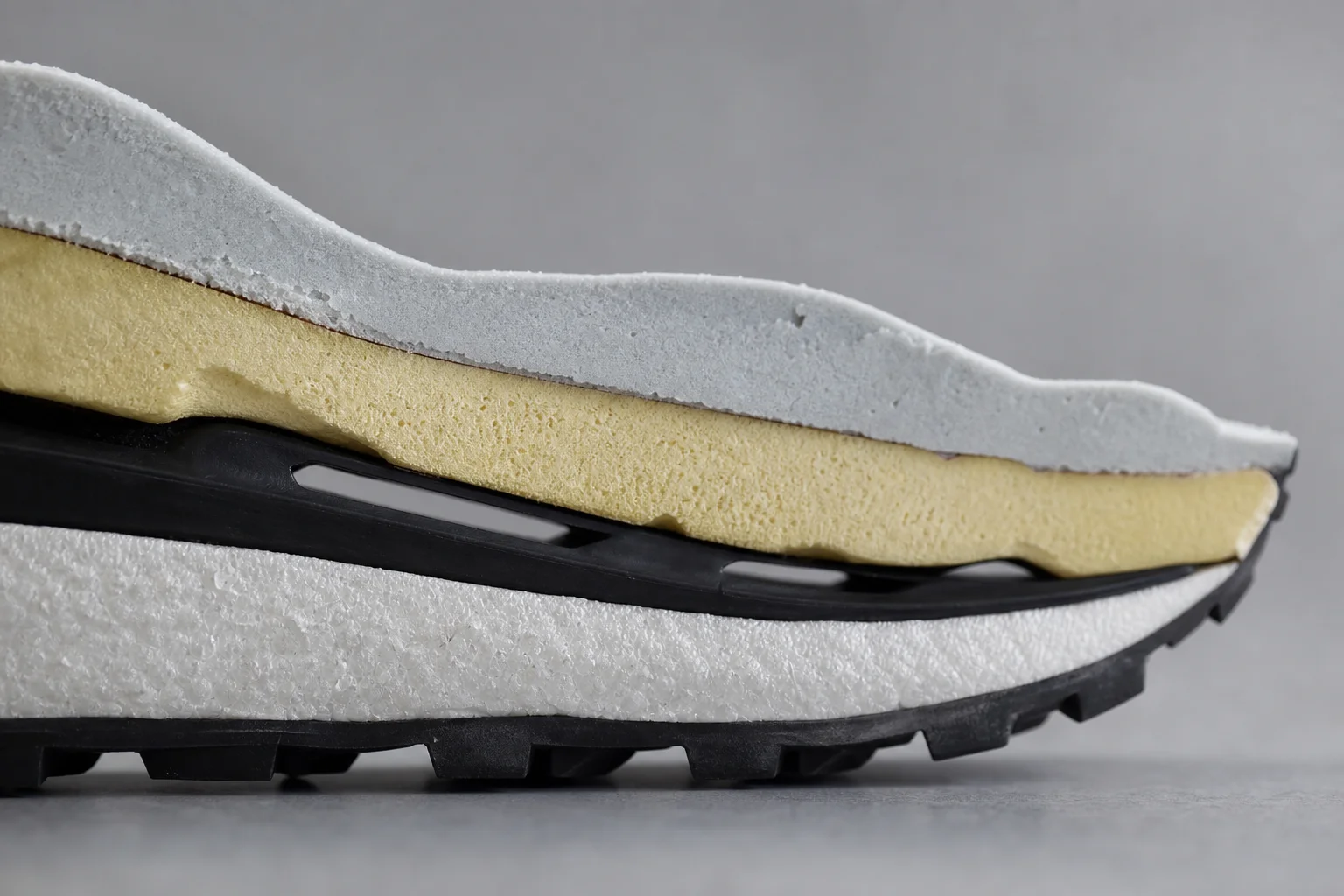 Close-up of trail running shoe midsole showing foam structure and protective plate