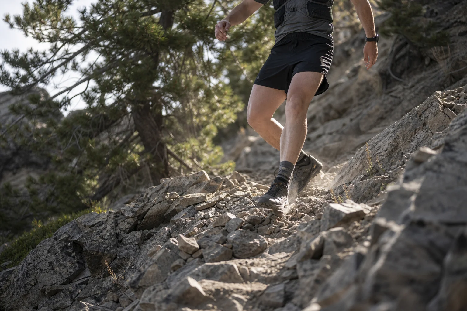 Trail runner descending a rocky slope with careful foot placement on technical terrain