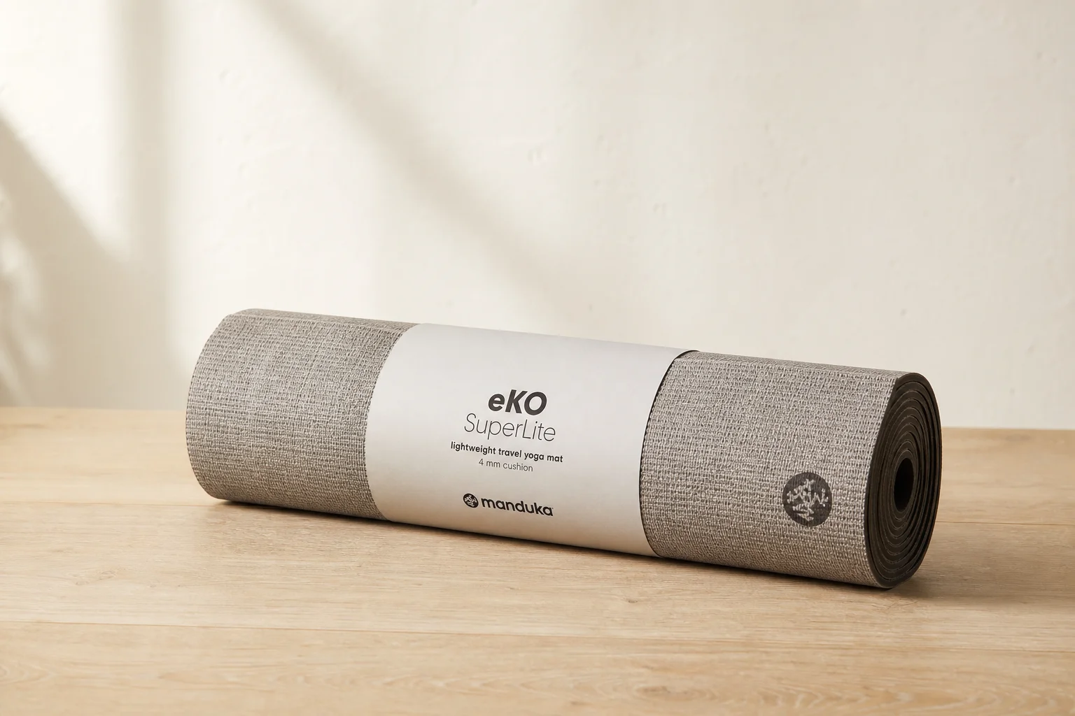 Seven different yoga mats arranged on a wooden floor showing variety of styles and colors