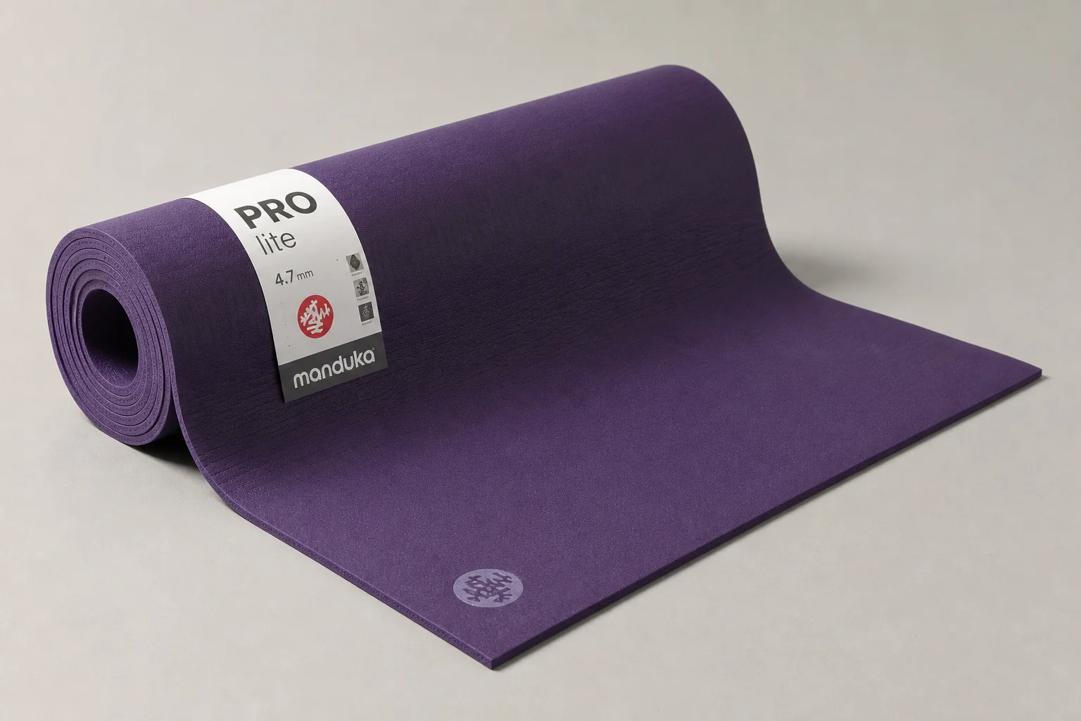Seven different yoga mats arranged on a wooden floor showing variety of styles and colors