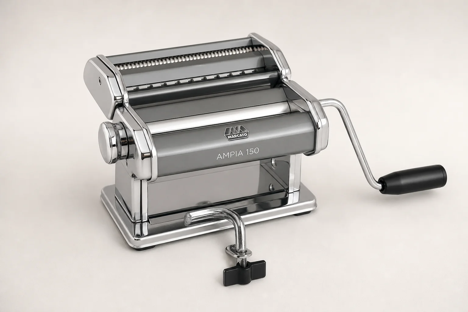 Five pasta makers arranged on wood surface including hand-crank and powered models
