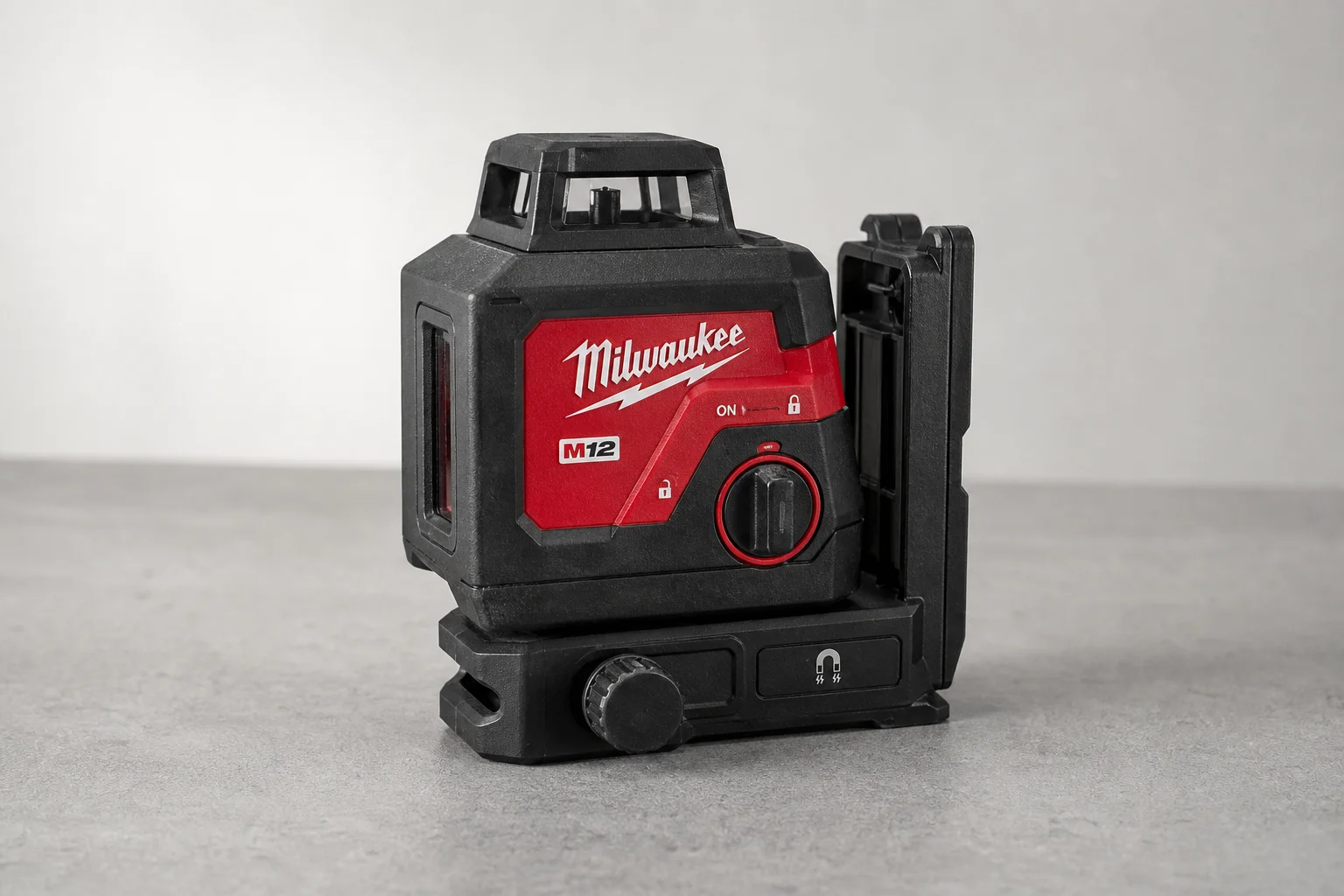 Milwaukee M12 four-point laser on grey surface showing base and controls
