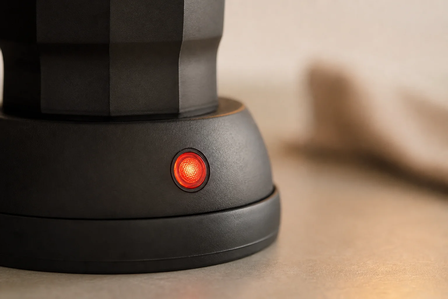 Close-up of moka pot heating element with red indicator light glowing