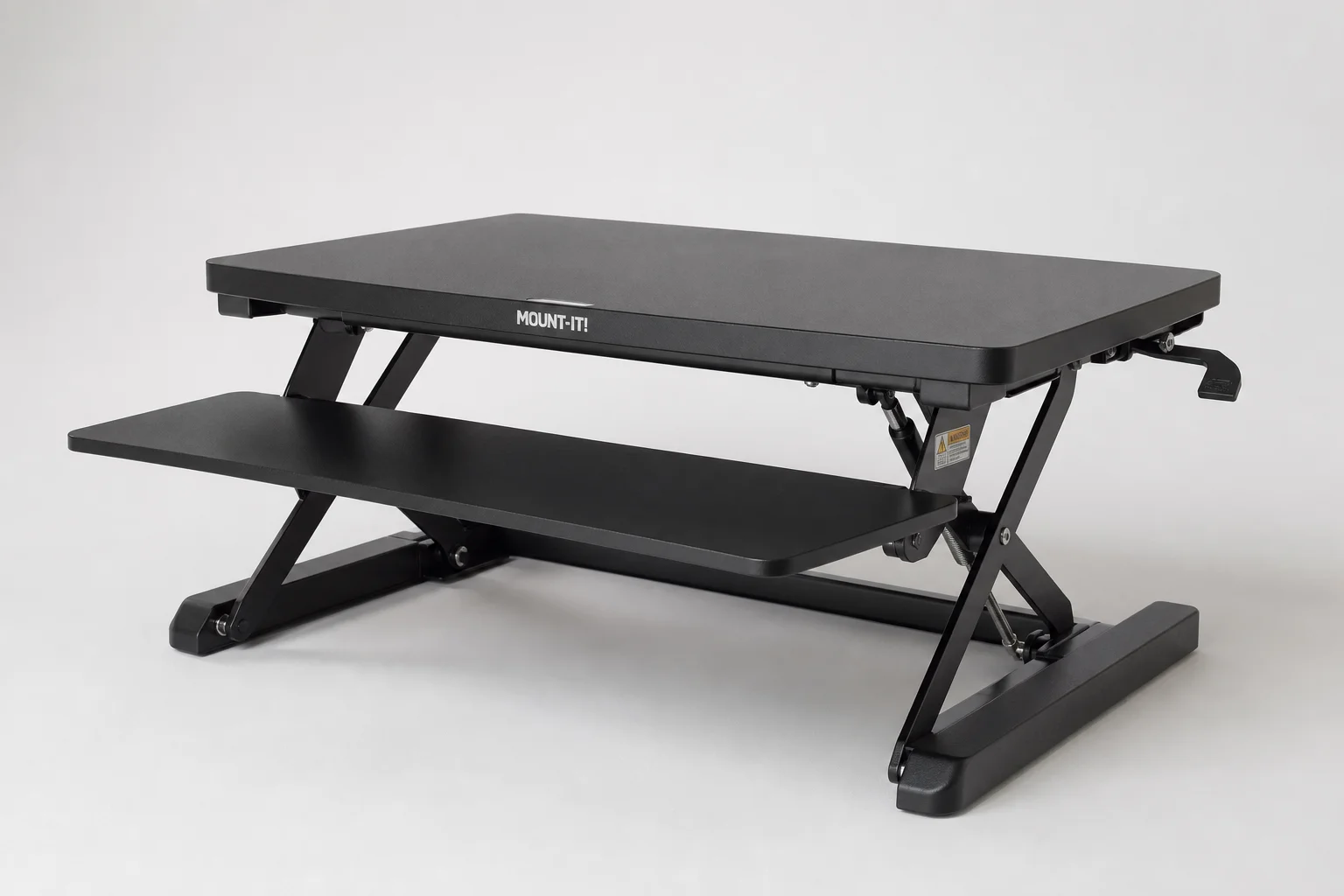Three standing desk converters displayed on a light wood desk surface