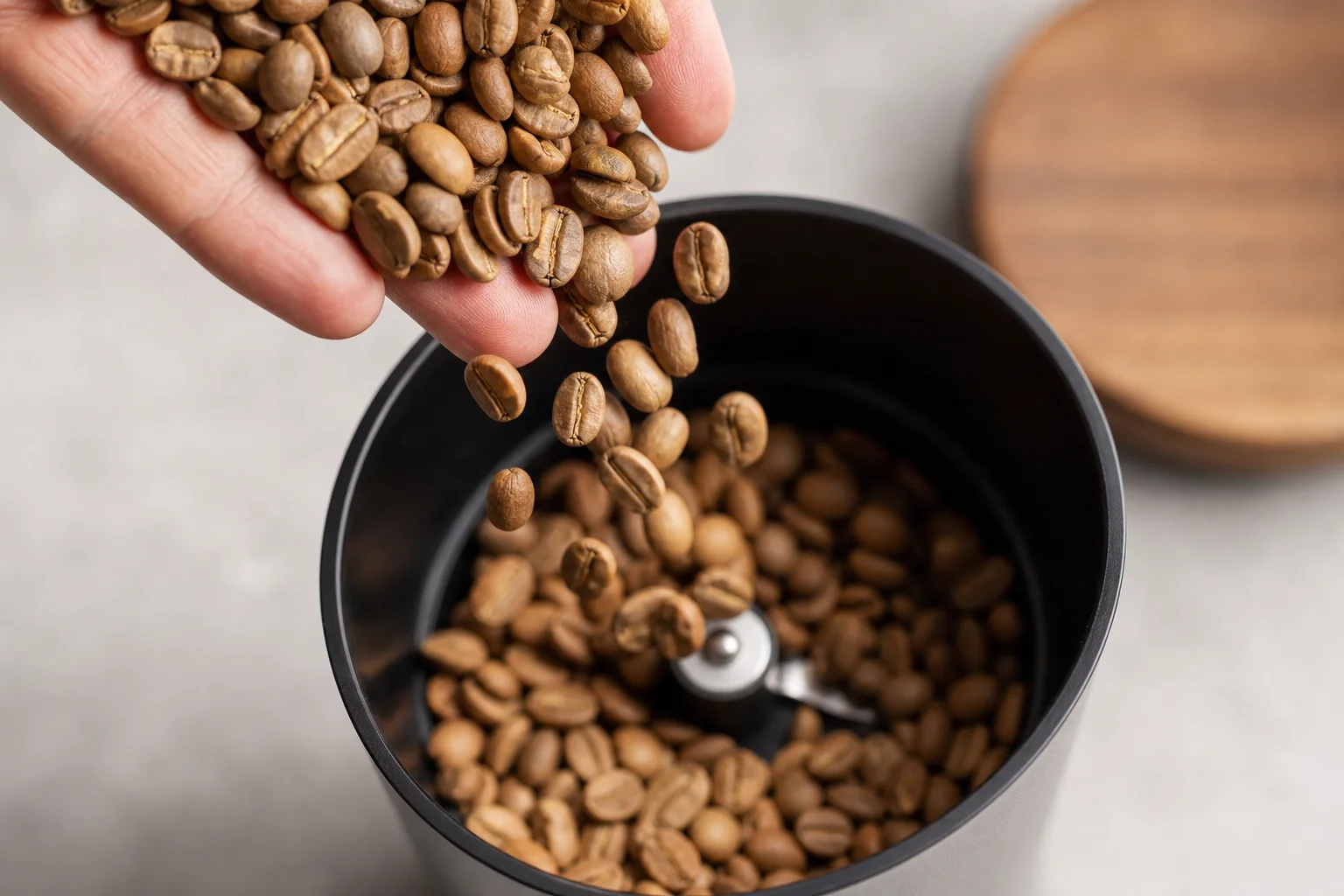 Coffee beans being poured into a grinder funnel from above