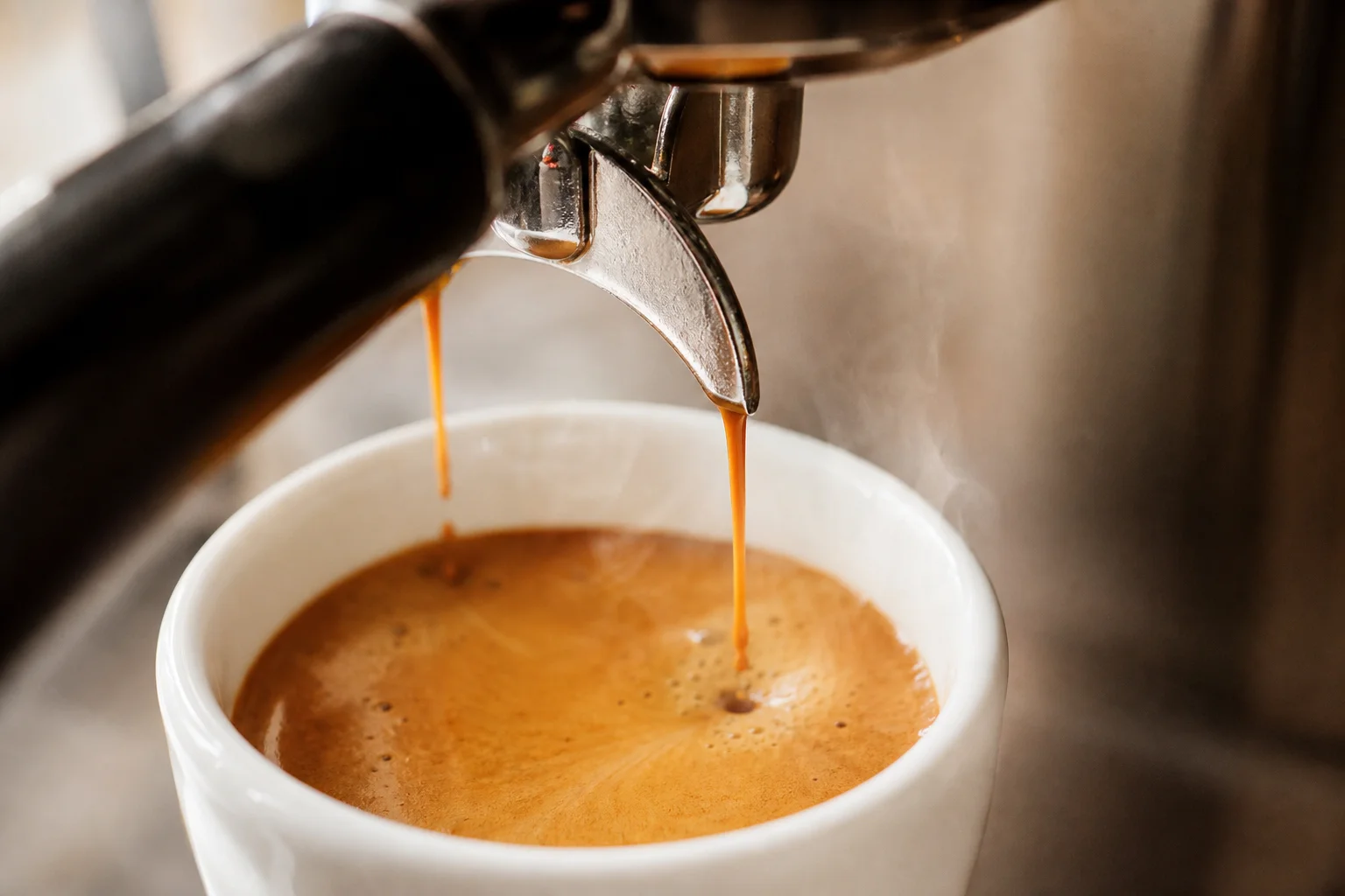 Espresso pouring into a white cup with rich crema