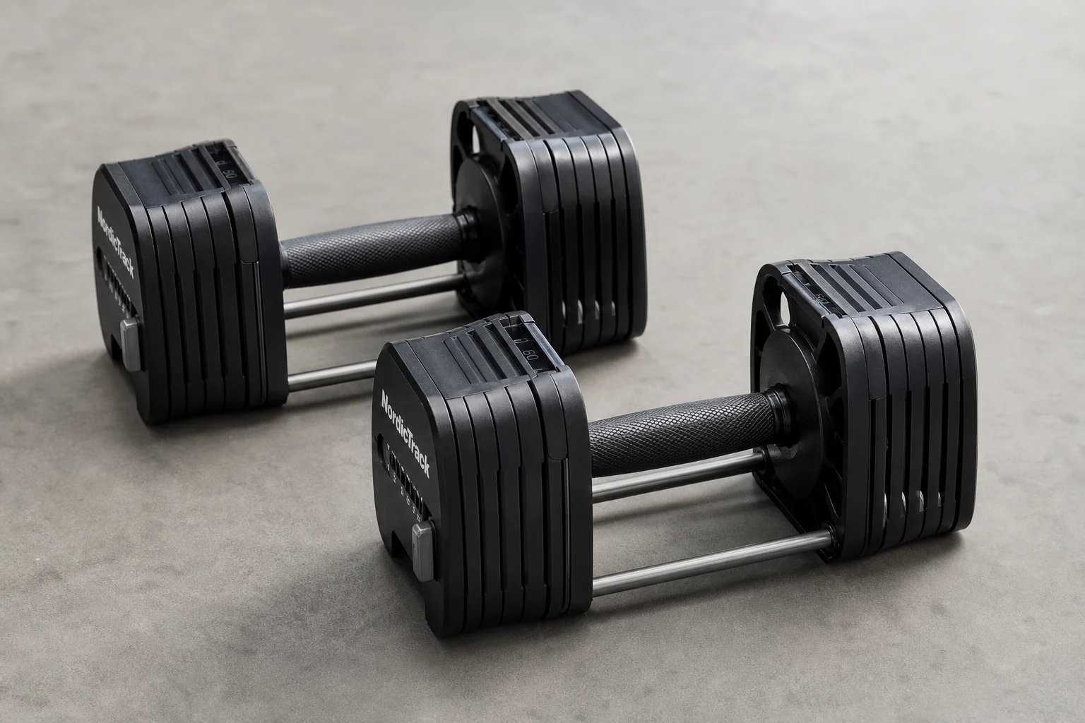 Seven different adjustable dumbbell models arranged on concrete surface